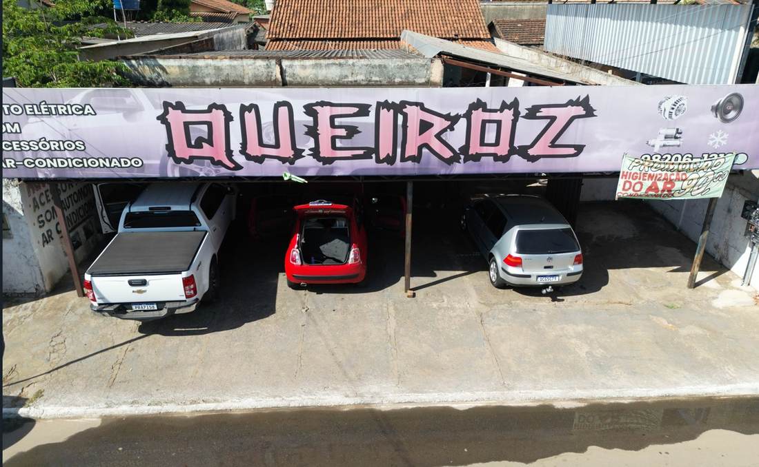 Fachada real da Queiroz Centro Eletro Automotivo em Goiânia, com veículos de clientes estacionados na oficina
